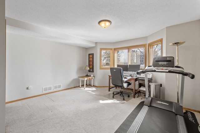 carpeted office space with visible vents, a textured ceiling, and baseboards