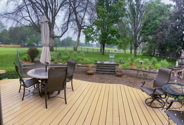 wooden deck featuring outdoor dining space, a lawn, and a fenced backyard