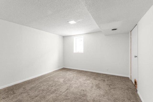 carpeted spare room featuring visible vents, baseboards, and a textured ceiling