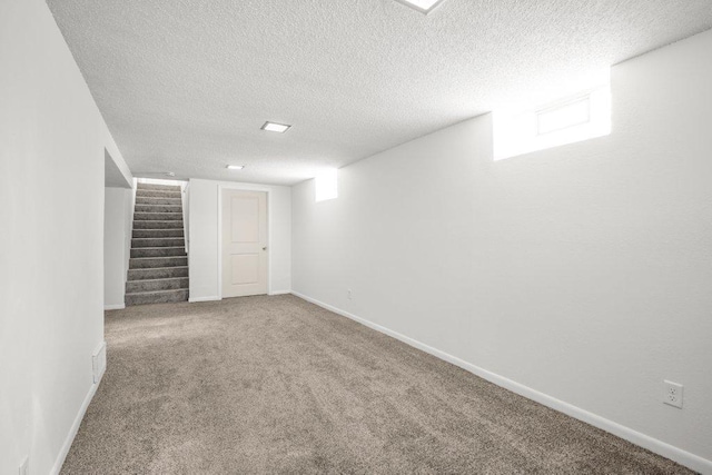 below grade area featuring a textured ceiling, stairway, carpet, and baseboards