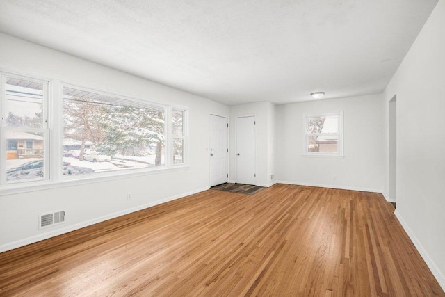 unfurnished room featuring baseboards, visible vents, and wood finished floors