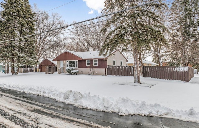 snow covered property featuring a fenced front yard