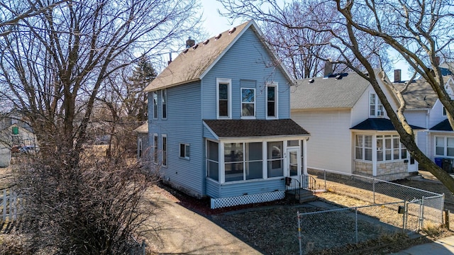 traditional-style home with fence, roof with shingles, entry steps, and a sunroom