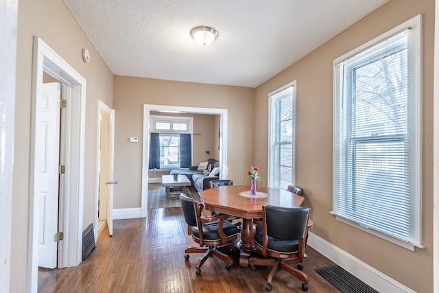 dining room with visible vents, a textured ceiling, baseboards, and wood finished floors