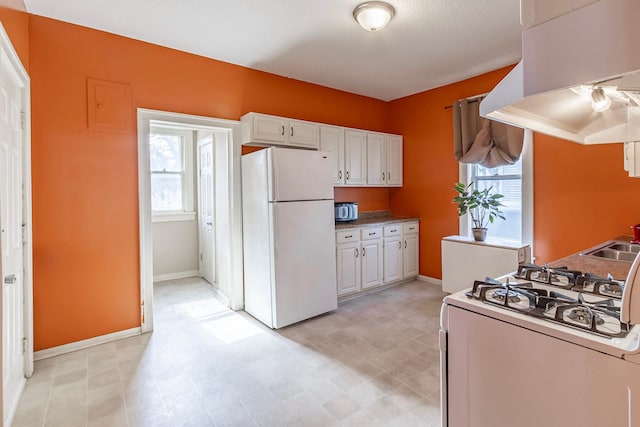 kitchen featuring ventilation hood, light floors, white cabinets, white appliances, and a sink