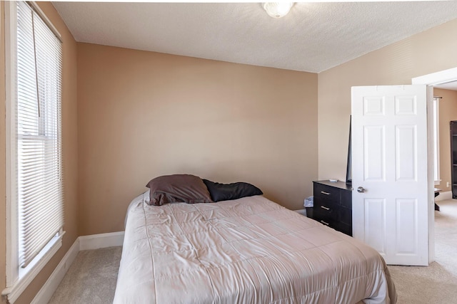 bedroom with light colored carpet, a textured ceiling, and baseboards