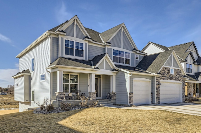 craftsman house featuring a shingled roof, covered porch, concrete driveway, stone siding, and a front lawn