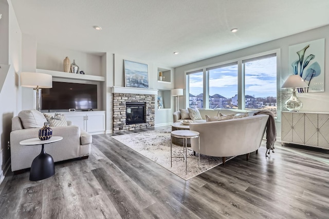 living area with built in shelves, recessed lighting, a fireplace, and wood finished floors