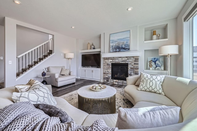 living area with recessed lighting, a fireplace, wood finished floors, built in features, and stairs