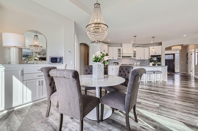 dining area with an inviting chandelier, arched walkways, and recessed lighting