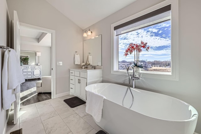 bathroom featuring baseboards, visible vents, lofted ceiling, vanity, and a freestanding tub