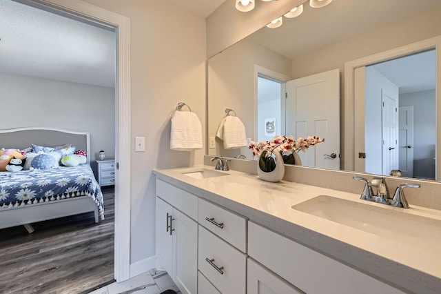 full bathroom with double vanity, ensuite bath, a sink, and baseboards