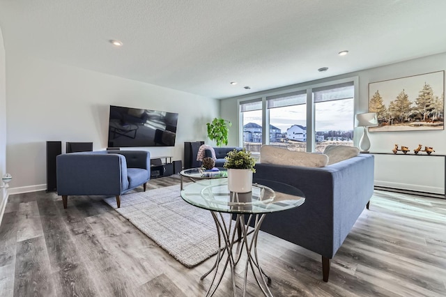 living area with recessed lighting, a textured ceiling, baseboards, and wood finished floors