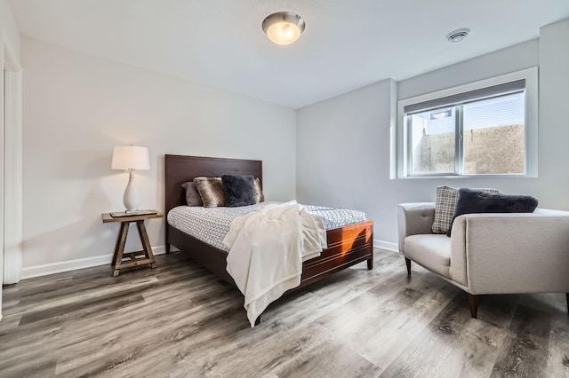 bedroom featuring wood finished floors, visible vents, and baseboards