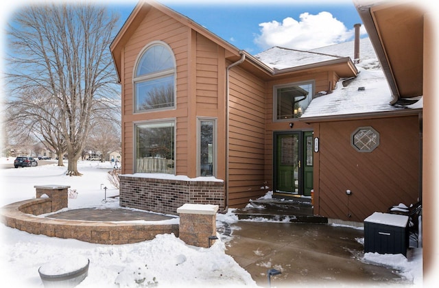 view of snowy exterior featuring brick siding