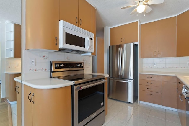 kitchen with tasteful backsplash, light countertops, appliances with stainless steel finishes, light tile patterned flooring, and a textured ceiling