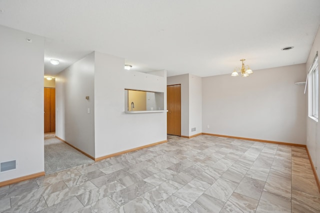 spare room with baseboards, visible vents, and a notable chandelier