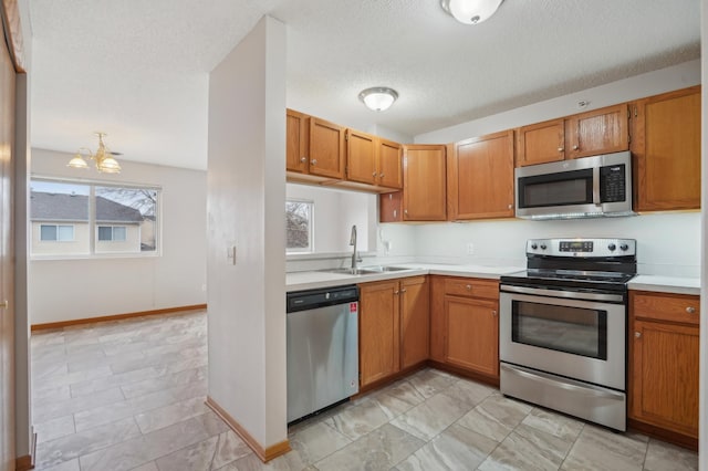 kitchen featuring stainless steel appliances, a sink, light countertops, and brown cabinets