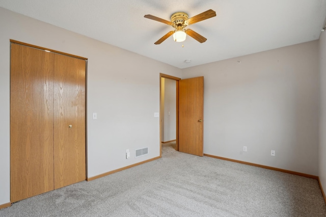 unfurnished bedroom with ceiling fan, visible vents, baseboards, a closet, and carpet