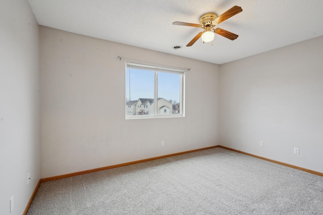 carpeted spare room with ceiling fan and baseboards