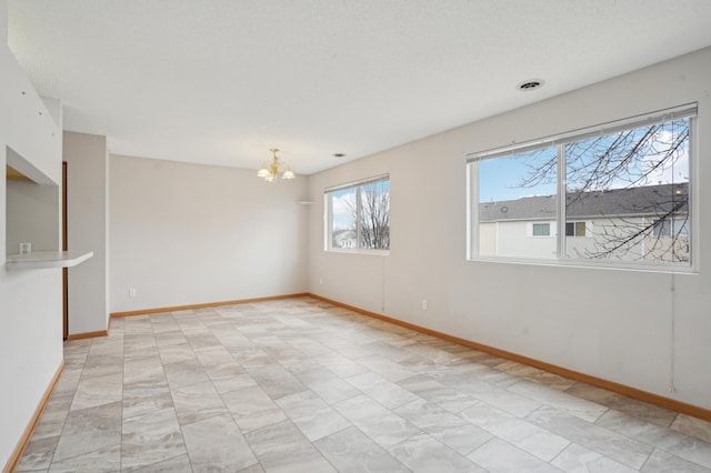 empty room featuring an inviting chandelier, visible vents, and baseboards