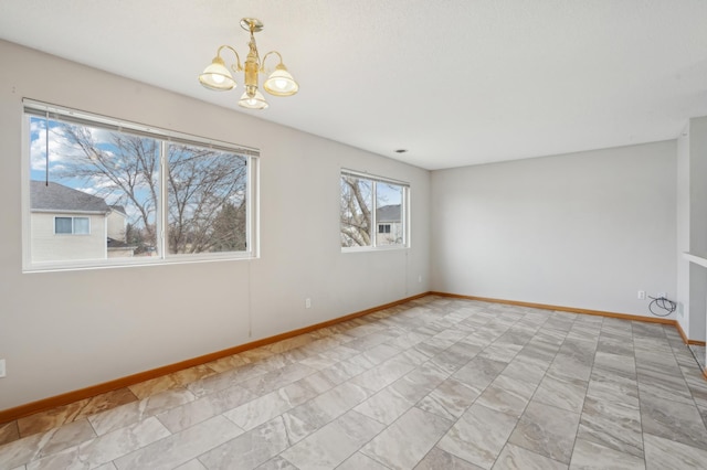 empty room featuring baseboards and a chandelier