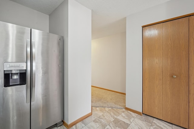 kitchen featuring light carpet, baseboards, a textured ceiling, and stainless steel fridge with ice dispenser