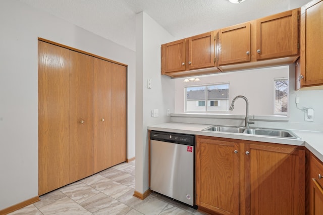 kitchen with a sink, brown cabinetry, light countertops, and dishwasher