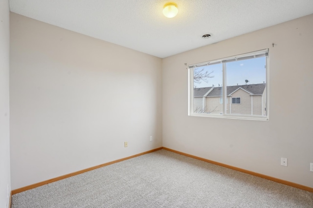 spare room with a textured ceiling, carpet floors, visible vents, and baseboards