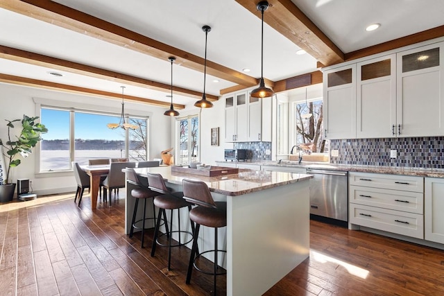 kitchen featuring dark wood-style floors, a center island, backsplash, and stainless steel dishwasher