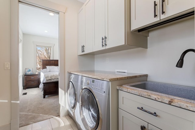 washroom featuring light colored carpet, a sink, visible vents, cabinet space, and washing machine and clothes dryer