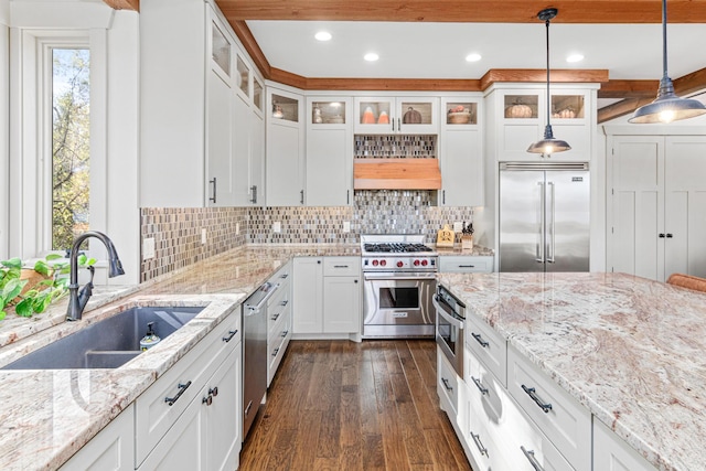 kitchen featuring dark wood-style flooring, high end appliances, backsplash, white cabinetry, and a sink