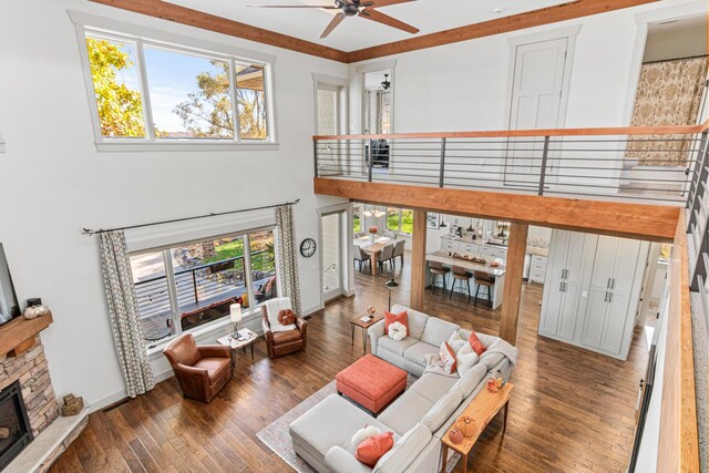 living area with visible vents, hardwood / wood-style flooring, ceiling fan, a high ceiling, and a fireplace