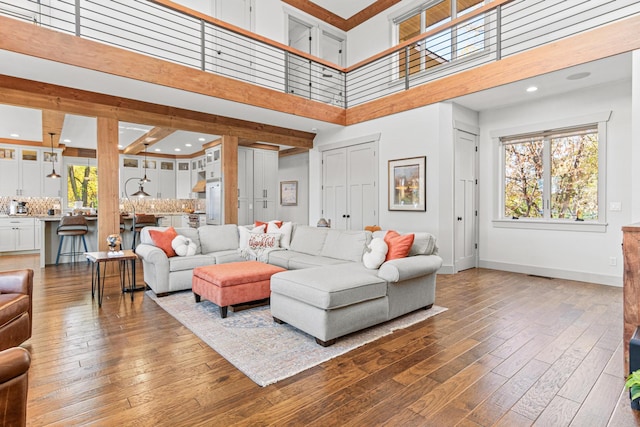 living area featuring a high ceiling, recessed lighting, hardwood / wood-style flooring, and baseboards