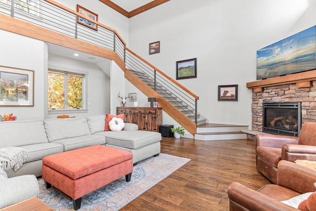 living room featuring a stone fireplace, stairway, a high ceiling, and hardwood / wood-style flooring