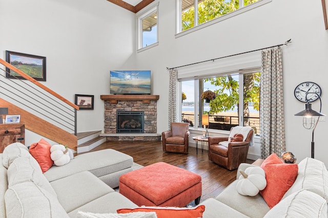 living room featuring a healthy amount of sunlight, hardwood / wood-style flooring, stairs, and a stone fireplace