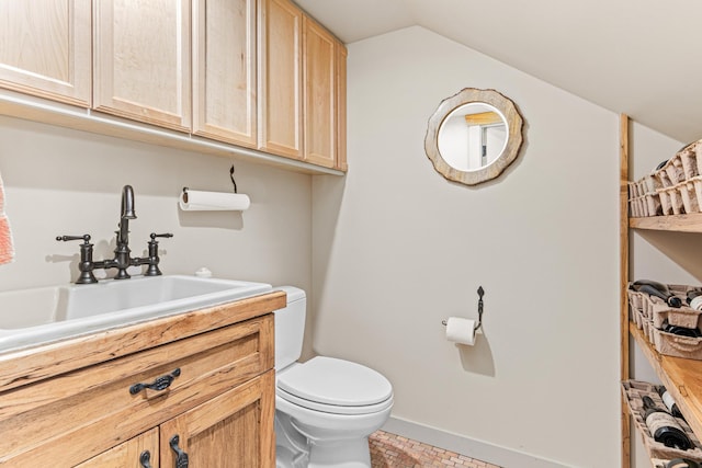 bathroom with lofted ceiling, baseboards, vanity, and toilet