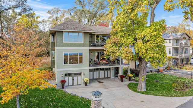 view of front of home featuring a balcony, driveway, a front lawn, and an attached garage