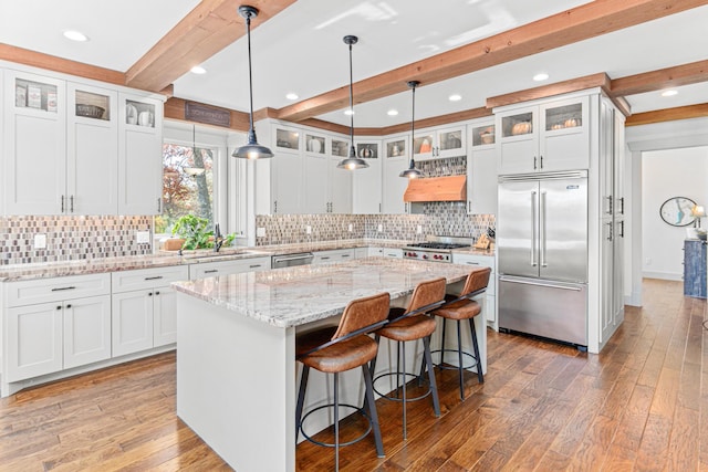 kitchen with stainless steel appliances, a sink, beamed ceiling, light wood-style floors, and a kitchen island