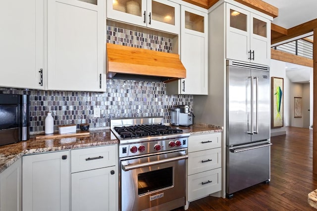 kitchen featuring high end appliances, stone counters, and white cabinetry