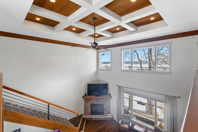 living area featuring a stone fireplace, ceiling fan, beamed ceiling, dark wood-style floors, and recessed lighting