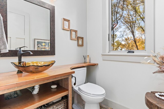 half bathroom with toilet, a sink, and baseboards