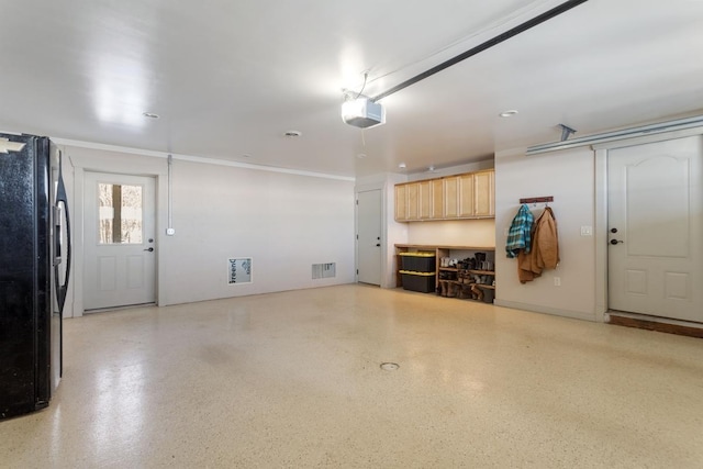 garage featuring a garage door opener, visible vents, and freestanding refrigerator