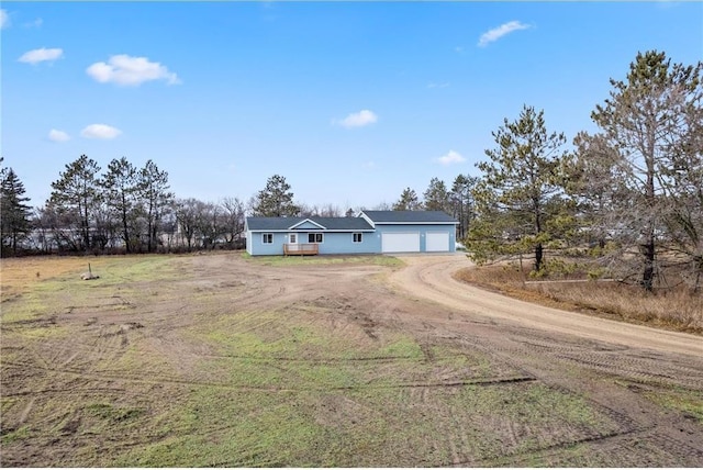 view of front of property with dirt driveway and a garage