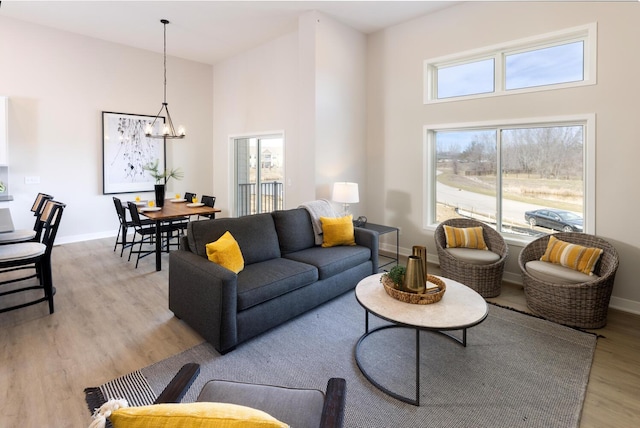 living area with an inviting chandelier, light wood-style flooring, and baseboards