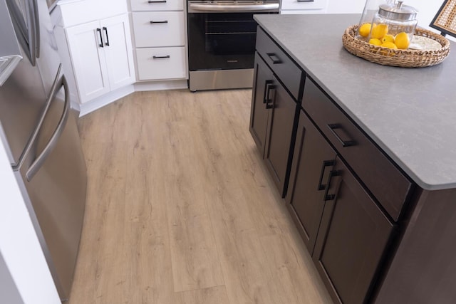 kitchen featuring fridge, light wood-type flooring, stainless steel range with electric stovetop, and white cabinetry