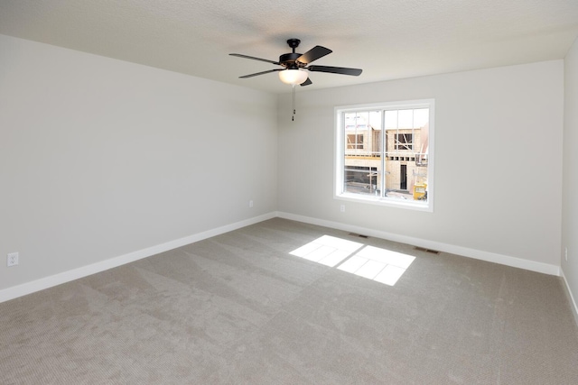 spare room with visible vents, baseboards, ceiling fan, carpet flooring, and a textured ceiling