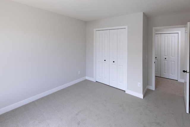 unfurnished bedroom featuring carpet flooring, baseboards, and a closet