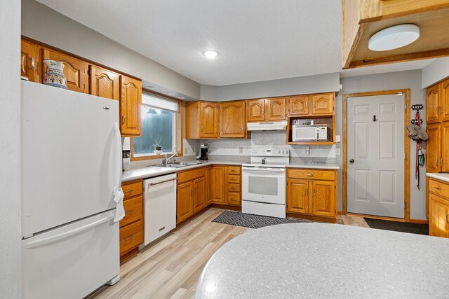 kitchen with white appliances, light countertops, a sink, and under cabinet range hood