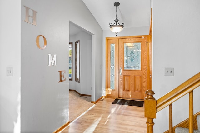 foyer entrance with wood finished floors, visible vents, baseboards, stairs, and vaulted ceiling